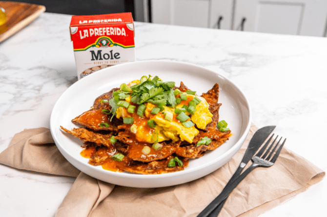 Plate of Mole Chilaquiles topped with scrambled eggs, green onions, and cilantro, made with La Preferida Mole sauce.