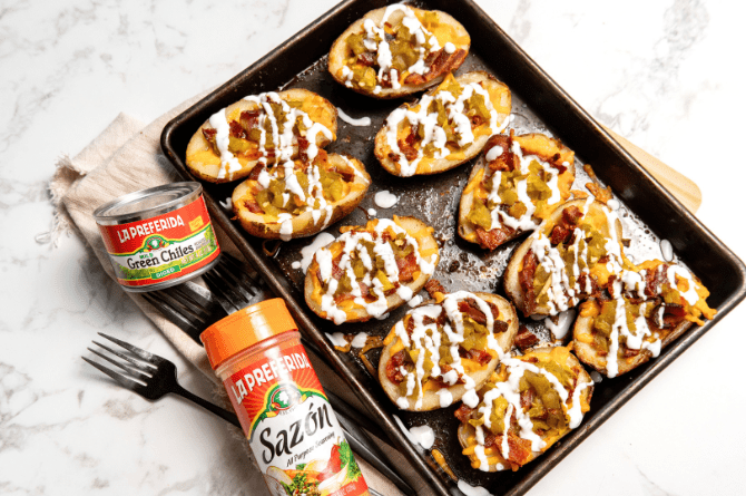Crispy baked potato skins topped with melted cheese, bacon bits, green chiles and a sour cream drizzle served as a Game Day appetizer