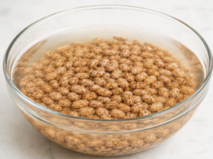 Pinto beans soaking in water before cooking to reduce cooking time and improve texture.